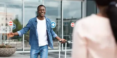 Man and woman reuniting warmly at an airport arrivals area